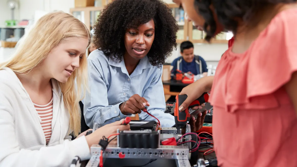 Three students work together on a robotics project in a classroom