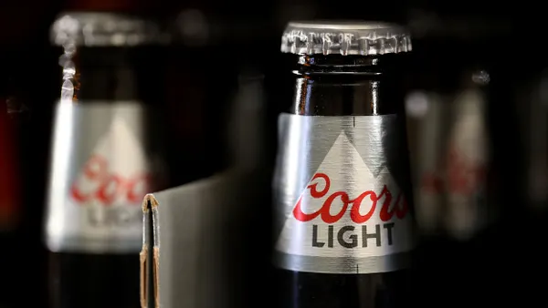 A closeup of a Coors Light bottle in a store refrigerator.