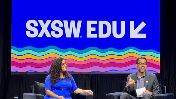 Two people are sitting in chairs on a stage. Behind them reads a screen saying "SXSW EDU"