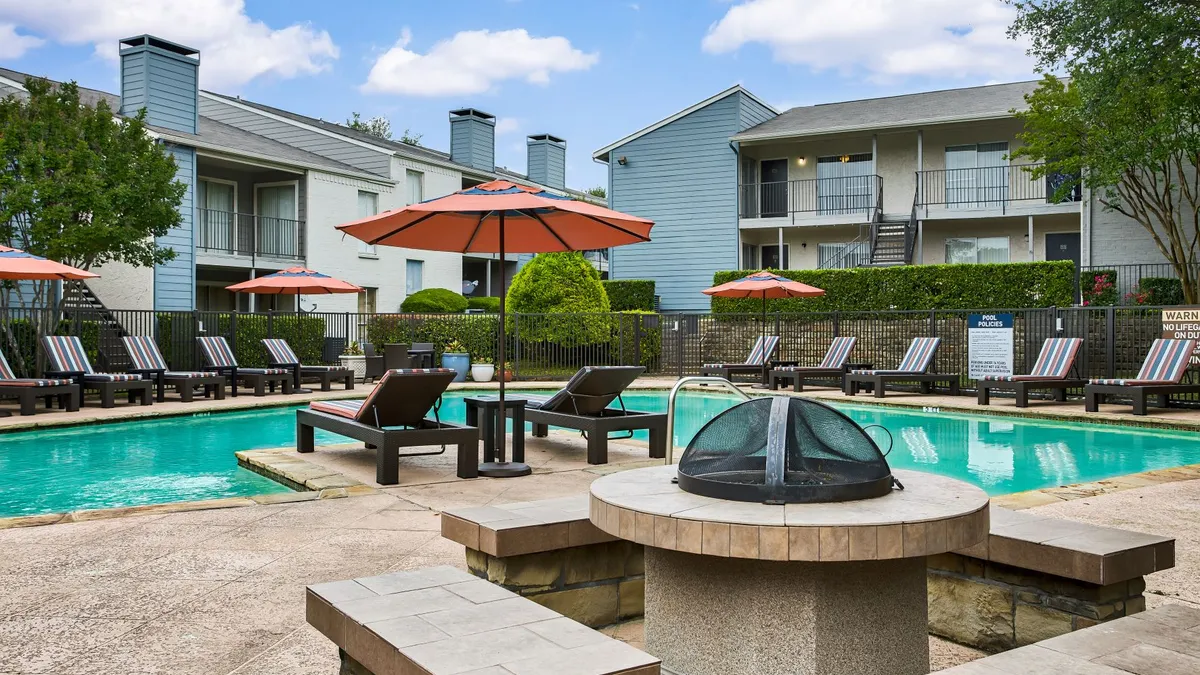 Two-story apartments with chairs and a pool in the foreground.