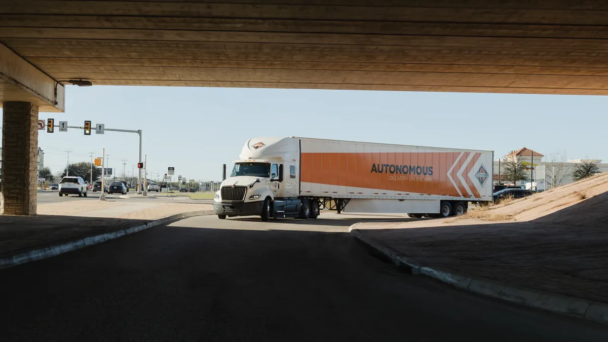 A Navistar truck drives under an overpass.