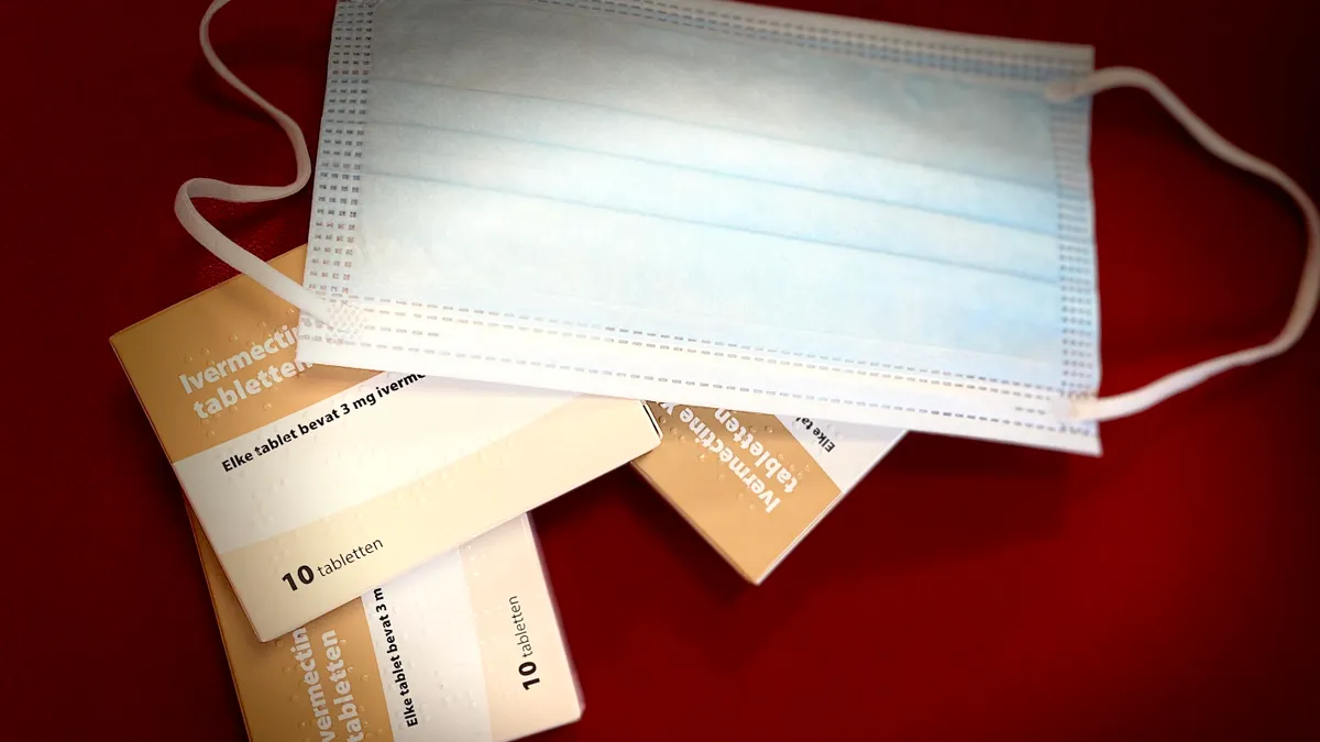 Ivermectin boxes and a mask against a red background