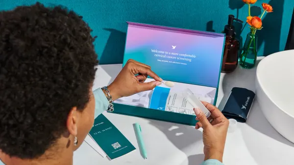 A women looks at Teal Health's at-home self-collection cervical cancer screening kit while at a counter.