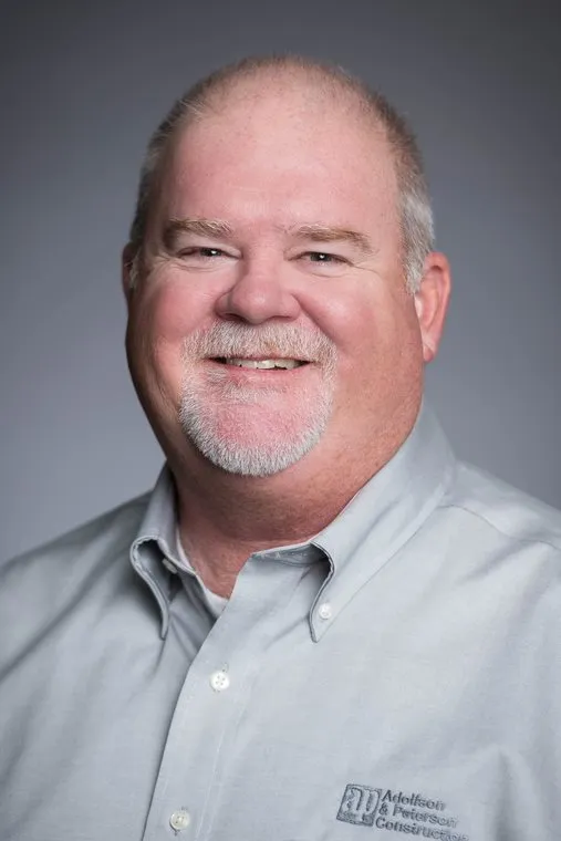 Man in a grey shirt and white hair and goatee.