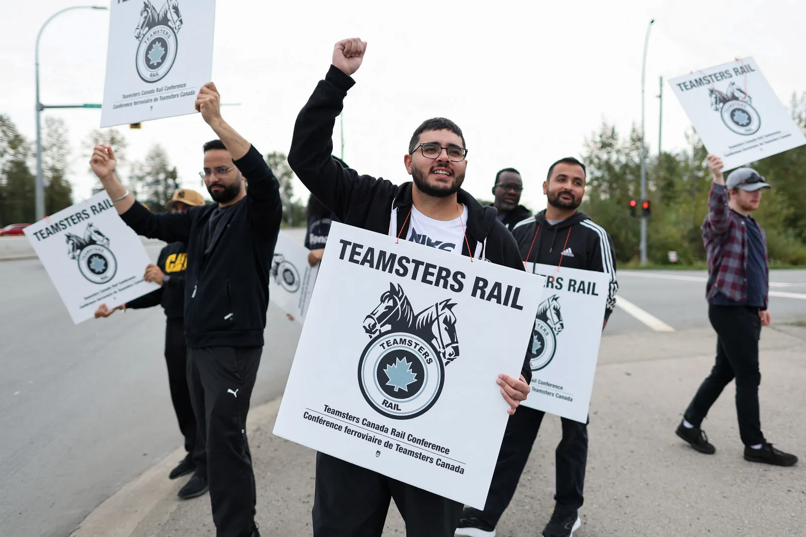 Union workers hold signs that say “Teamsters Rail” during a labor protest.