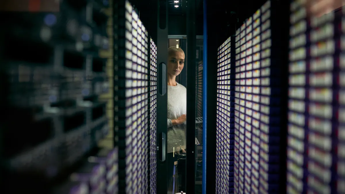 an engineer peers inside a glass door, looking at a serveroom