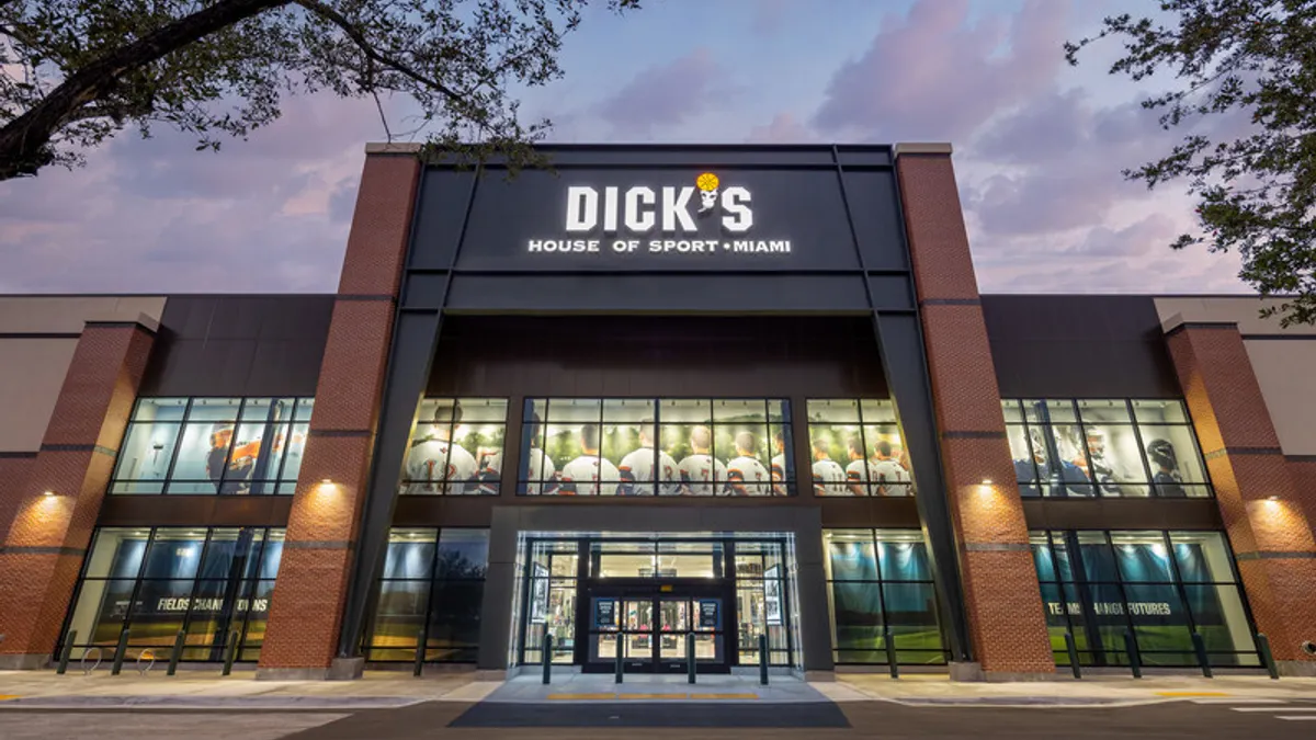A green and red brick Dick's storefront with trees in the foreground.