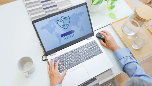 An overhead view of a person using a laptop connected virtual private network security application.