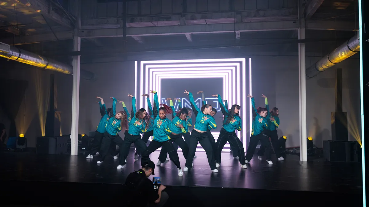 A group of dancers in matching outfits perform on a stage.