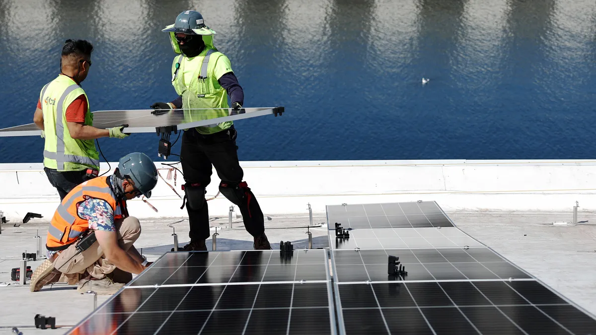 Workers install solar panels on a 4-acre solar rooftop atop AltaSea's research and development facility at the Port of Los Angeles.