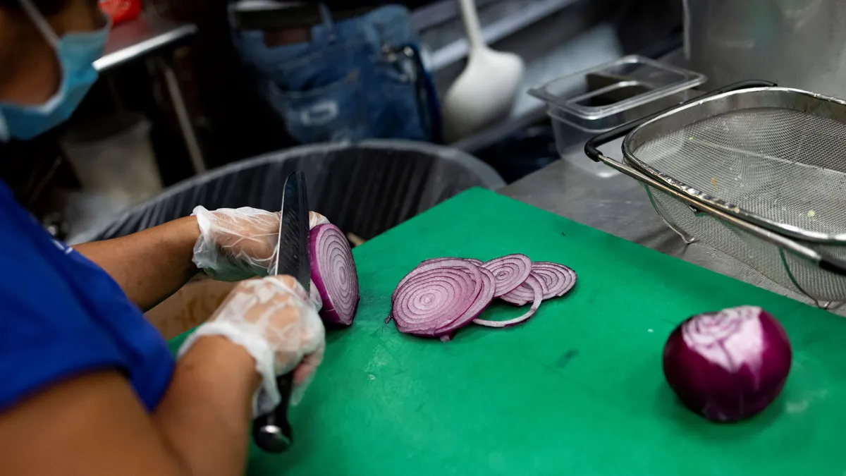 A cook cuts onions in the kitchen at Ben's Chili Bowl on August 22, 2022 in Washington, DC.