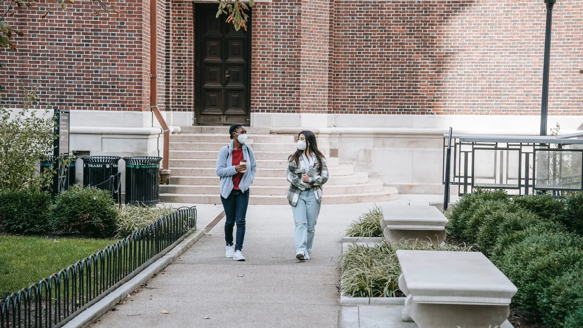 Two college students walk on a college campus