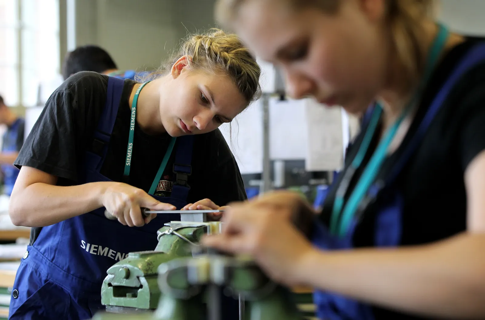 Female mechanical engineering trainees learn the basics of precision filing at a training center.