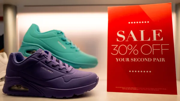 Two Skechers sneakers are pictured on a store display advertising a sale.