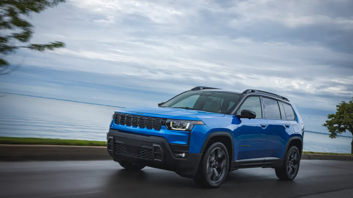 A blue 2026 Jeep Cherokee SUV driving on a road.