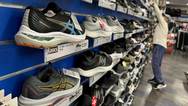 A wall of sneakers featuring the Asics logo is shown in a store.