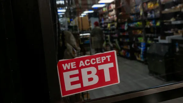 Close-up of a sign saying "We accept EBT" in a storefront window.