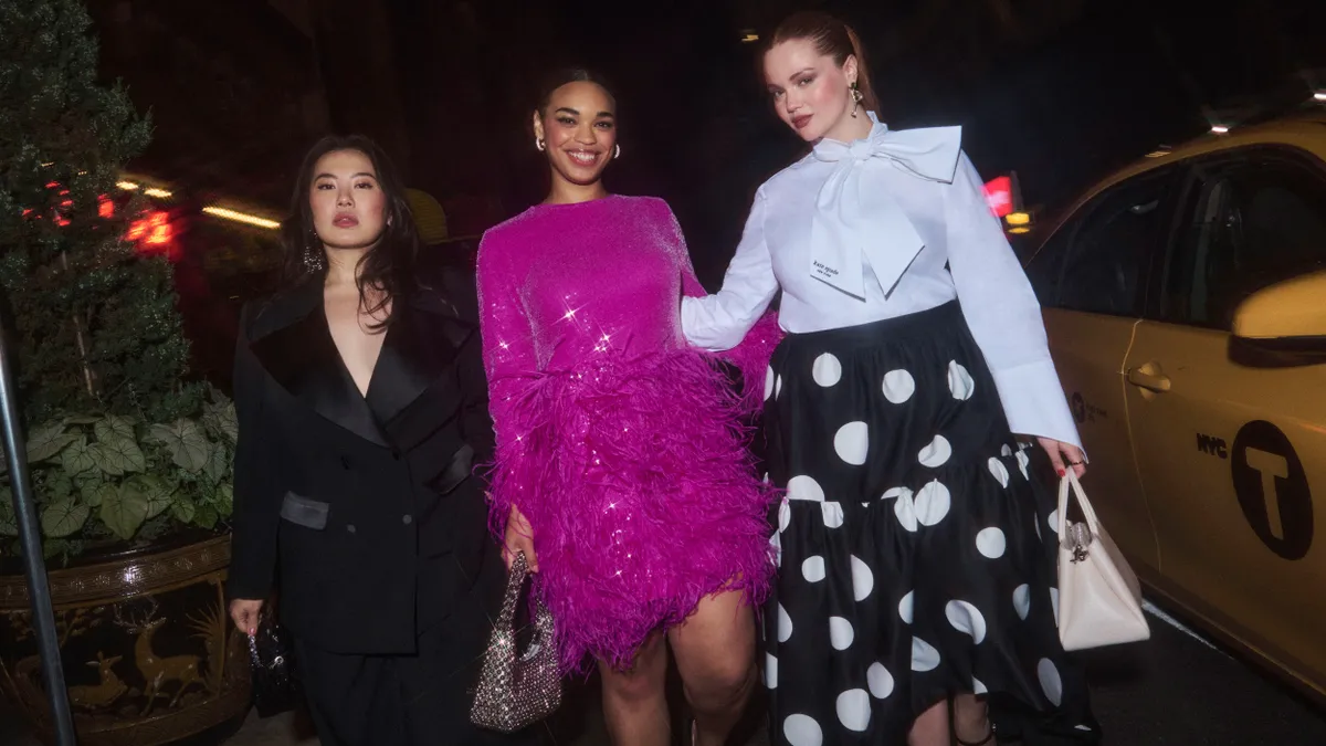 Three models wear items from the Kate Spade and Eloquii collaboration, including a suit, pink dress and a polka dot maxi skirt.