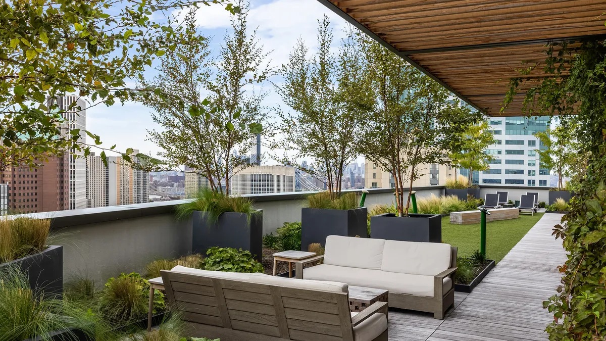 Exterior area in high-rise with couches and trees.