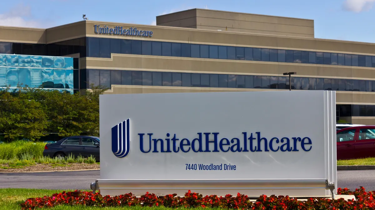 The exterior of the UnitedHealthcare office building with a large sign in the foreground that reads 'UnitedHealthcare, 7440 Woodland Drive'.