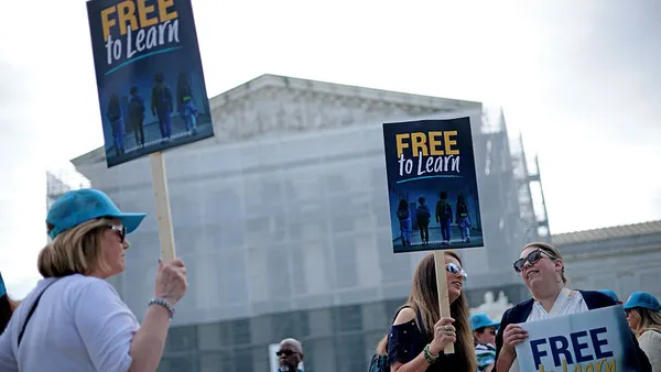 People are holding signs outside the U.S. Supreme Court building. The signs read "Free to learn"