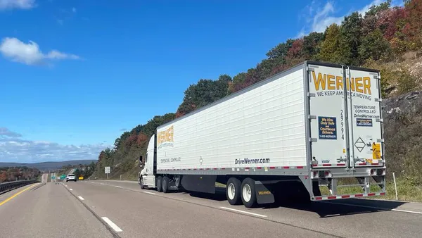 A Werner tractor-trailer on the interstate near a passenger vehicle.