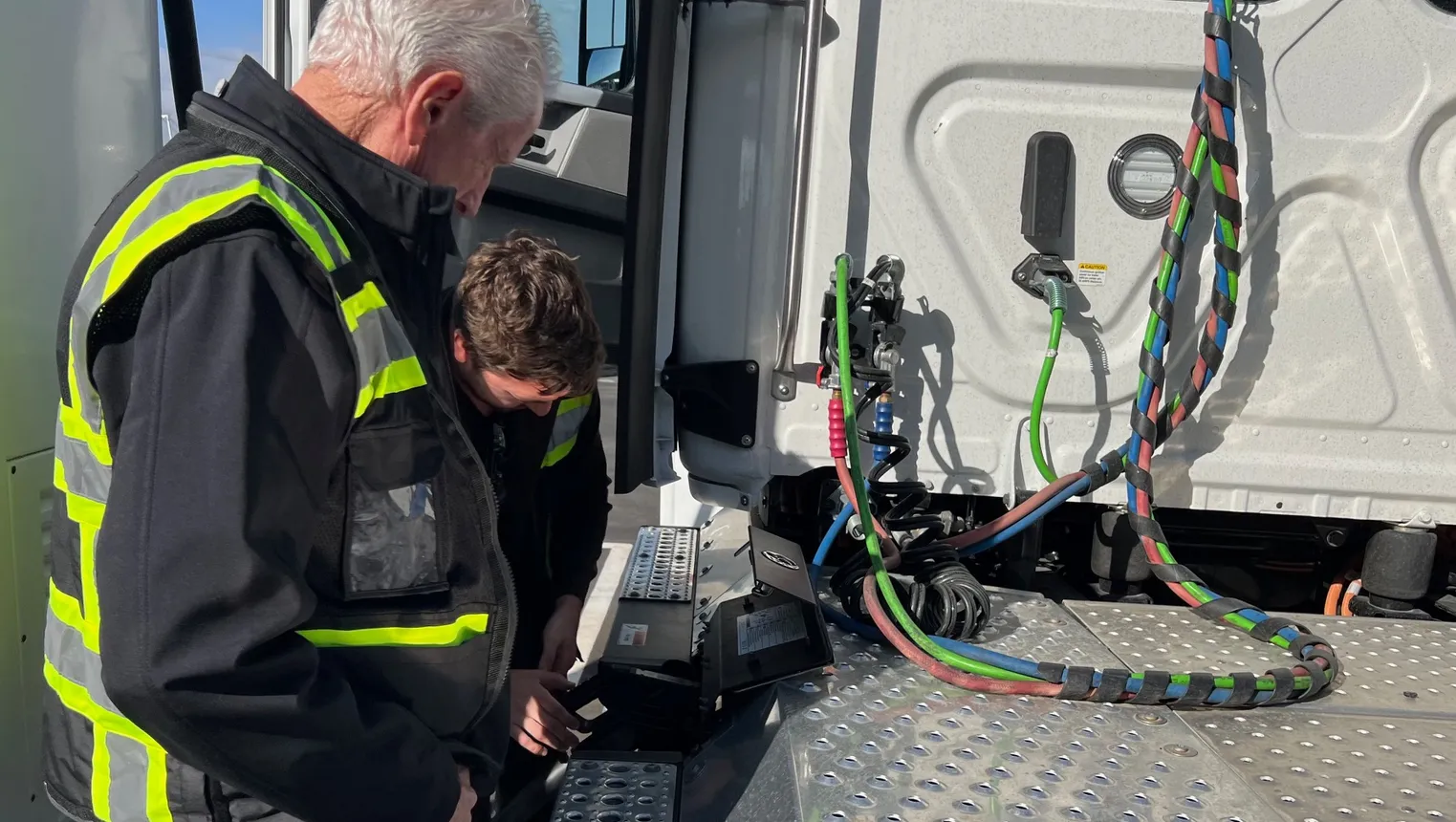 A Forum Mobility staffer helps a truck driver plug in an electric truck at a charging station.