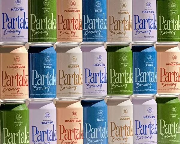 Close-up of various flavors of Partake Brewing's non-alcoholic beer in aluminum cans.