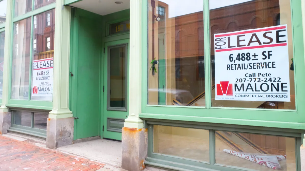 "For lease" signs in empty store windows trimmed in light green paint.