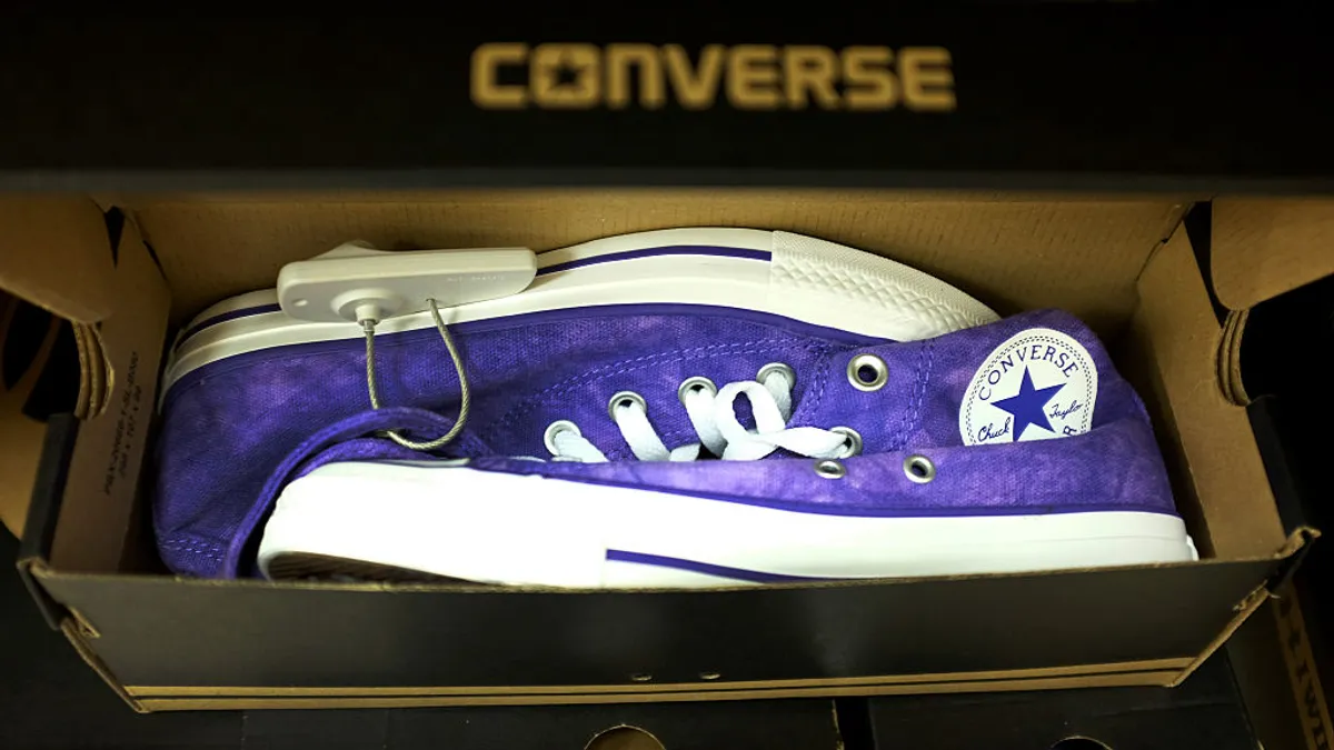 A closeup of purple Converse hightop shoes in a store display in a box.