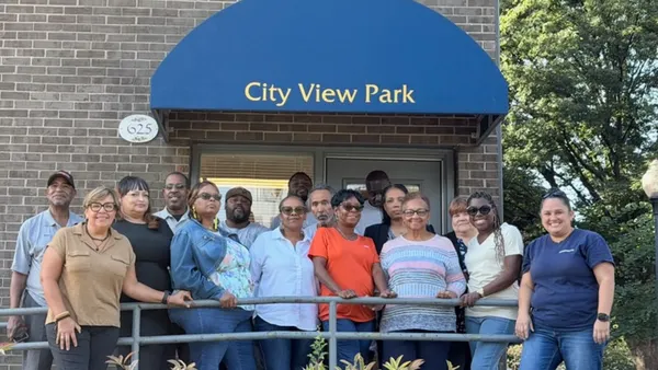 People standing in front of a brick apartment below a