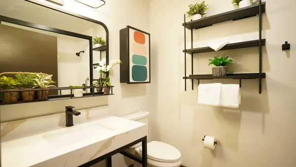 An image shows inside a guestroom bathroom at a Studio 6 Plus hotel.