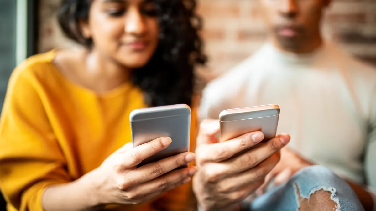 Two people sending money to each other through a digital wallet app on their smartphones.