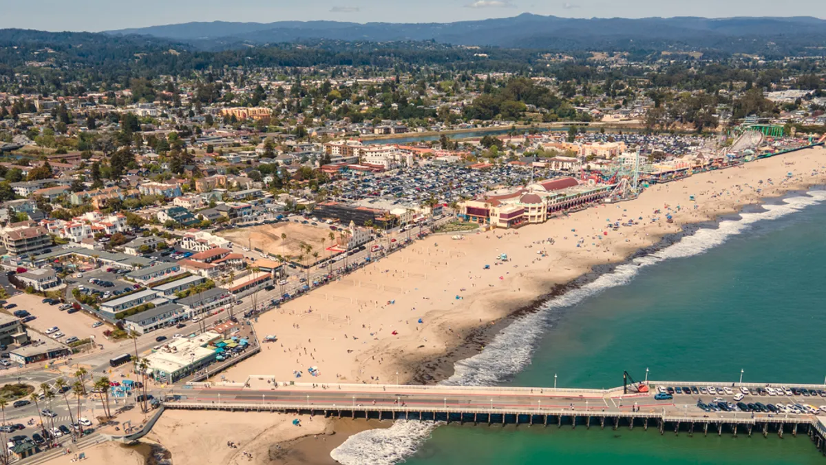 An aerial view of the iconic pier and boardwalk on the beach in Santa Cruz, California.