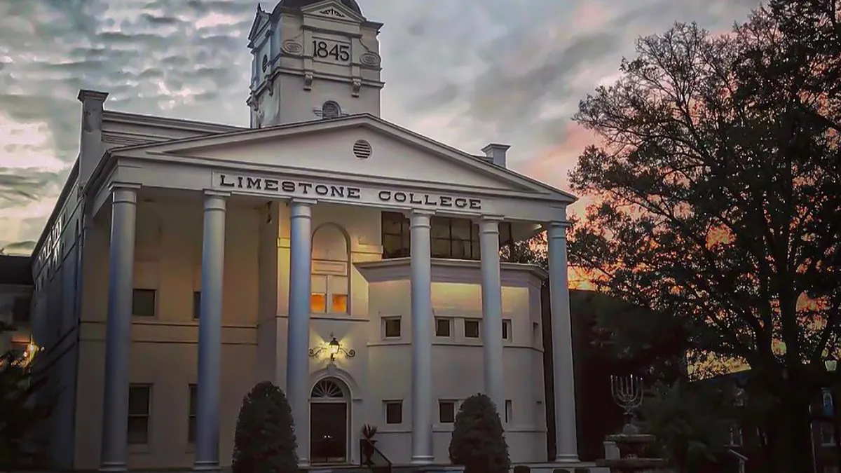 A white building with columns against the sunset.