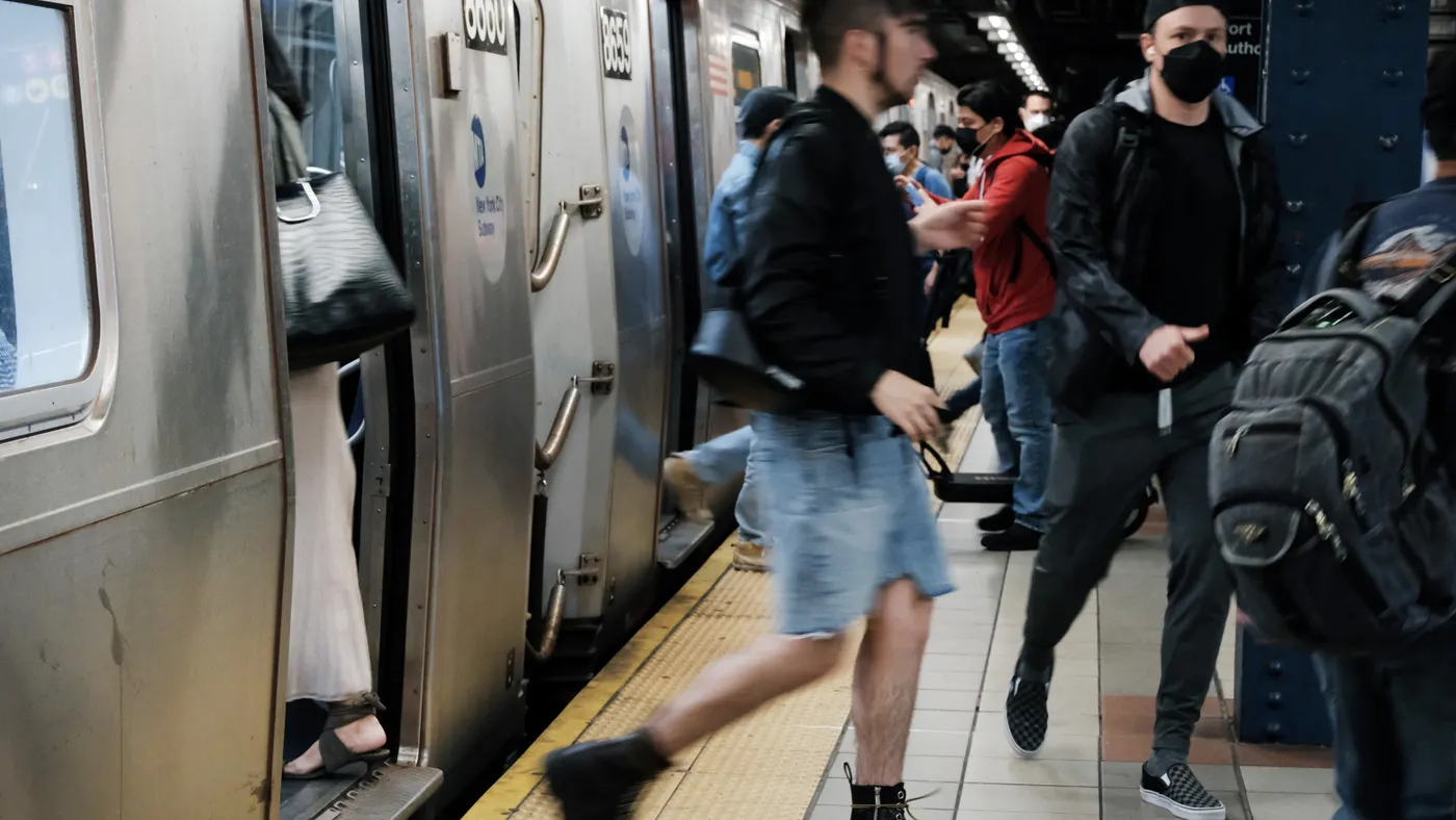 Many people exit and enter a silver New York City subway trains at a Manhattan underground station.