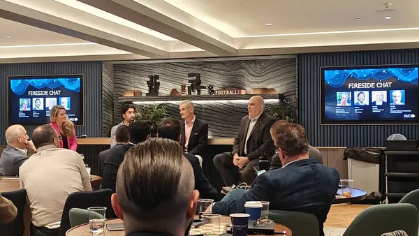 four-person panel in front of people who are seated at circular tables