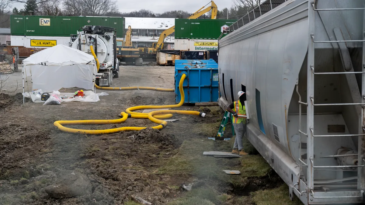 A worker cleans a train car at a train derailment site.