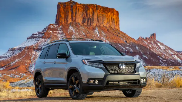 A 2021 Honda Passport SUV parked in the desert with snow-capped hills in the background.