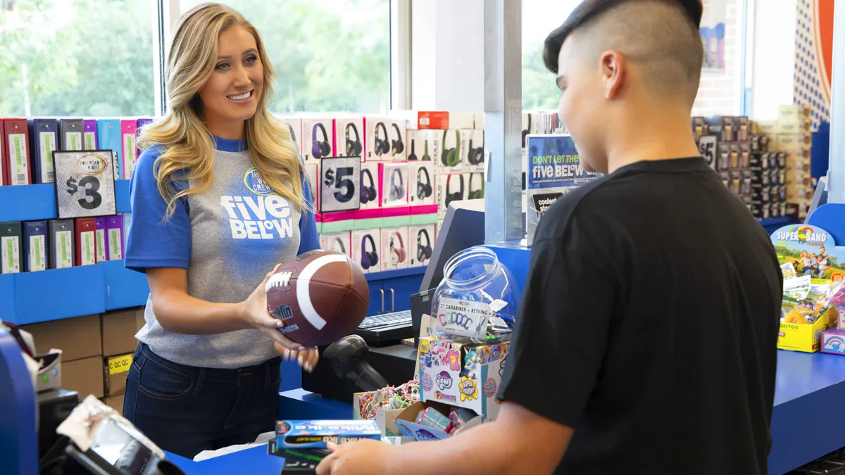 A Five Below employee assists a customer at the checkout counter