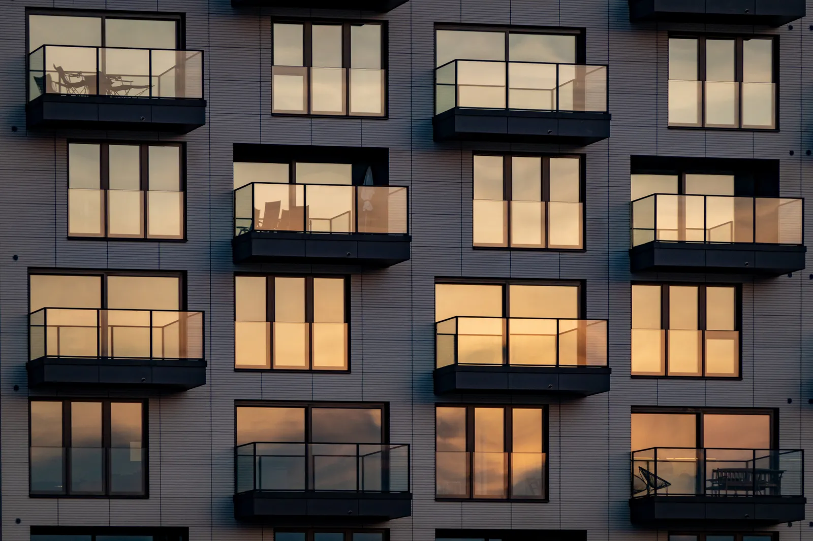 The evening sun is reflected in the modern apartment building with balconies.