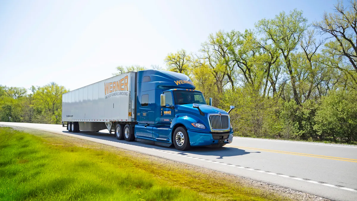 A truck on a road by grass and trees