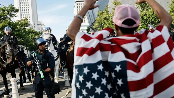 Protester wearing an American flag holds up his hands