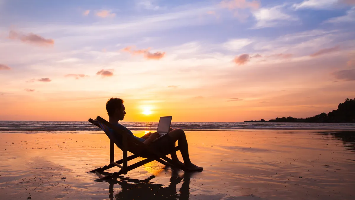 silhouette of happy business man with laptop working on the beach