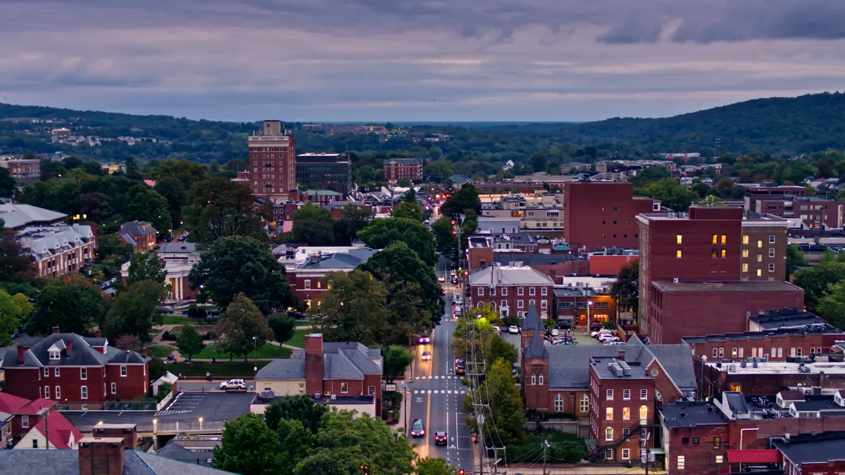 Aerial view of buildings with street running through the middle and hills in the background.