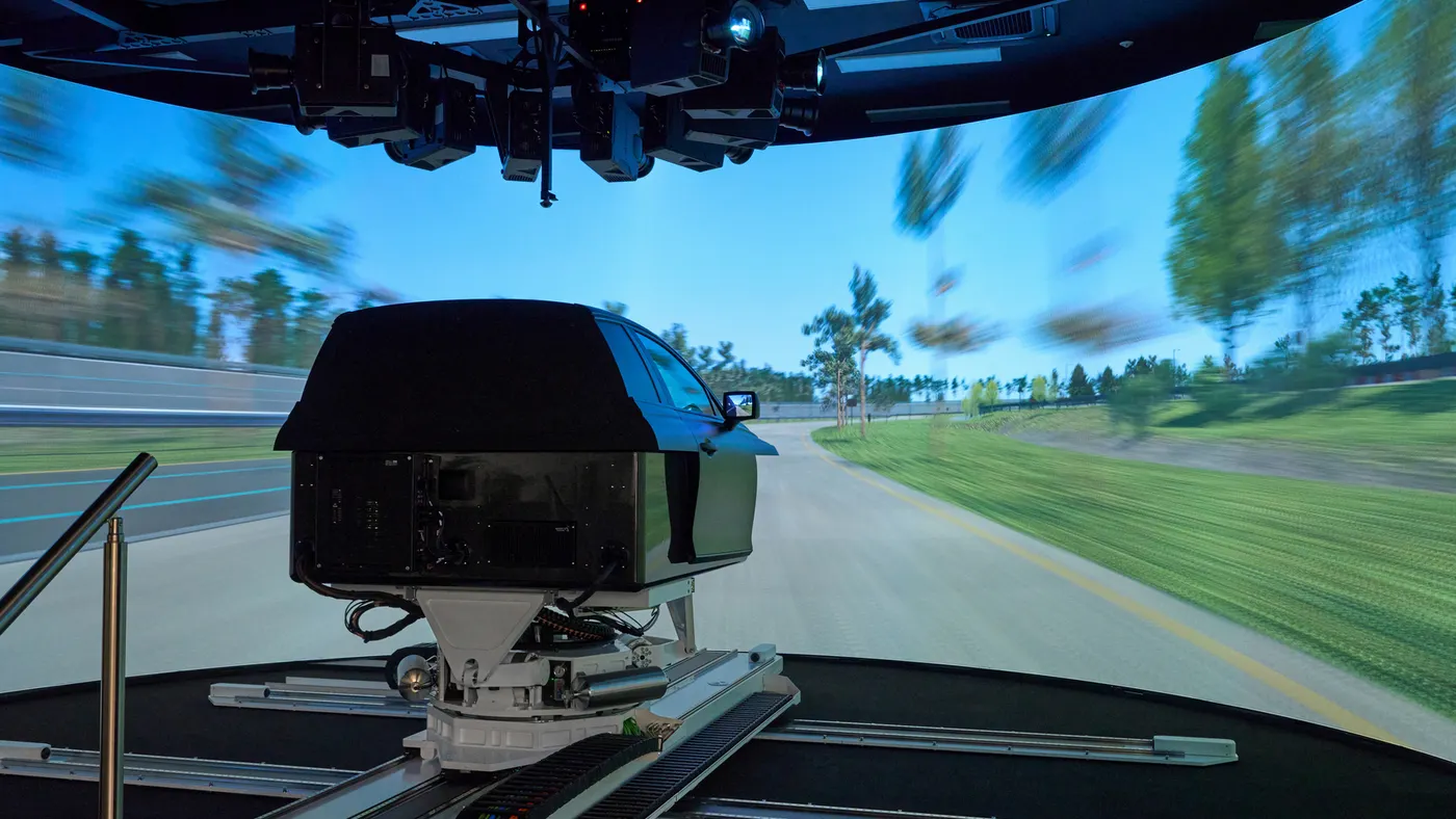 Hyundai's Driving Simulator in front of a large a 270-degree curved-display showing a test track that mimics real-world driving.