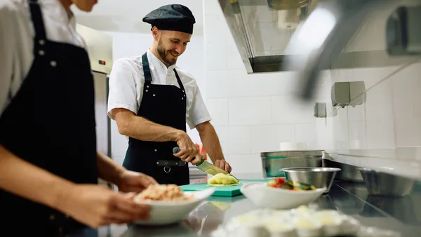 Happy cook preparing food while working in the kitchen in restaurant.