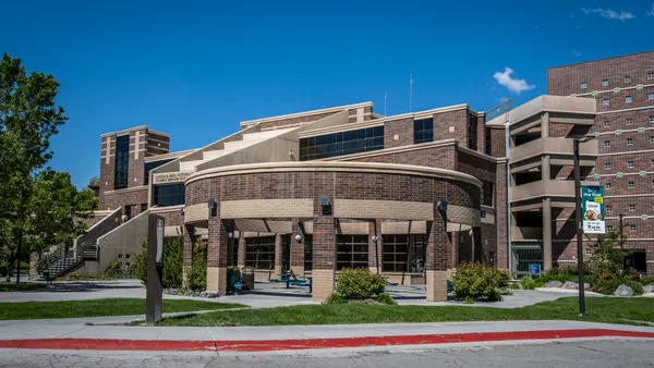 A brown building looms in the foreground on a clear, sunny day.