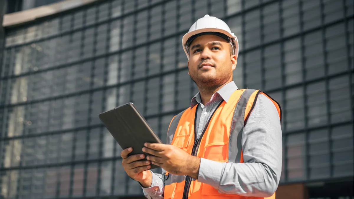 Confident asian engineer man Using tablet for checking and maintenance to inspection at modern home building construction.