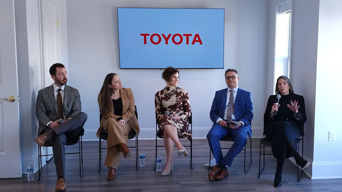 Five people sitting in chairs in a white, lit room.